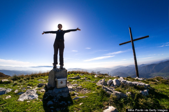 Woman with arms stretched out standing on summit